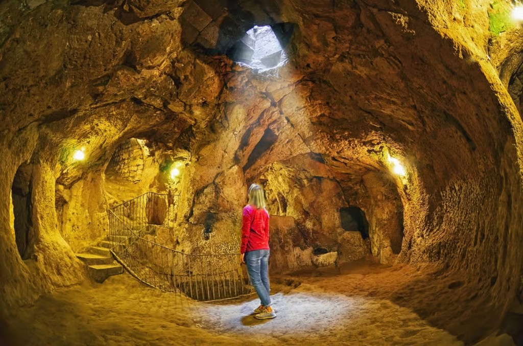 Guest looking up a Derinkuyu Underground City light shaft on the bookable Cappadocia Green Tour from The Owl Cave Hotel, Göreme