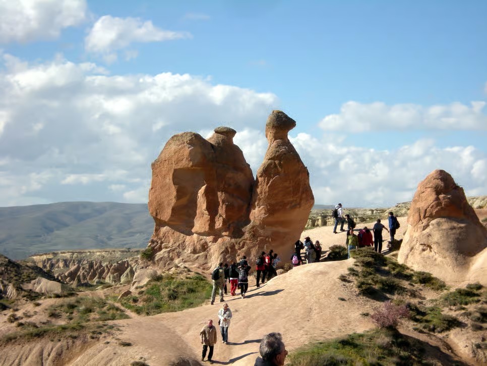 Guests approaching the camel-shaped rock in Devrent Valley on the bookable Cappadocia Red Tour from The Owl Cave Hotel
