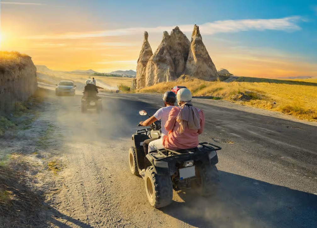 Guests on a quad at sunset past Love Valley fairy chimneys on the bookable Göreme Quad Safari from The Owl Cave Hotel