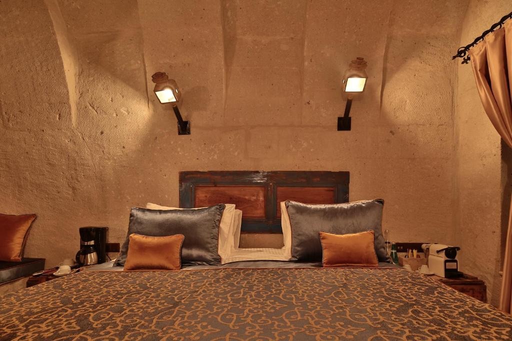 Deluxe Arch Room with View king bed with painted wooden headboard at The Owl Cave Hotel in Göreme