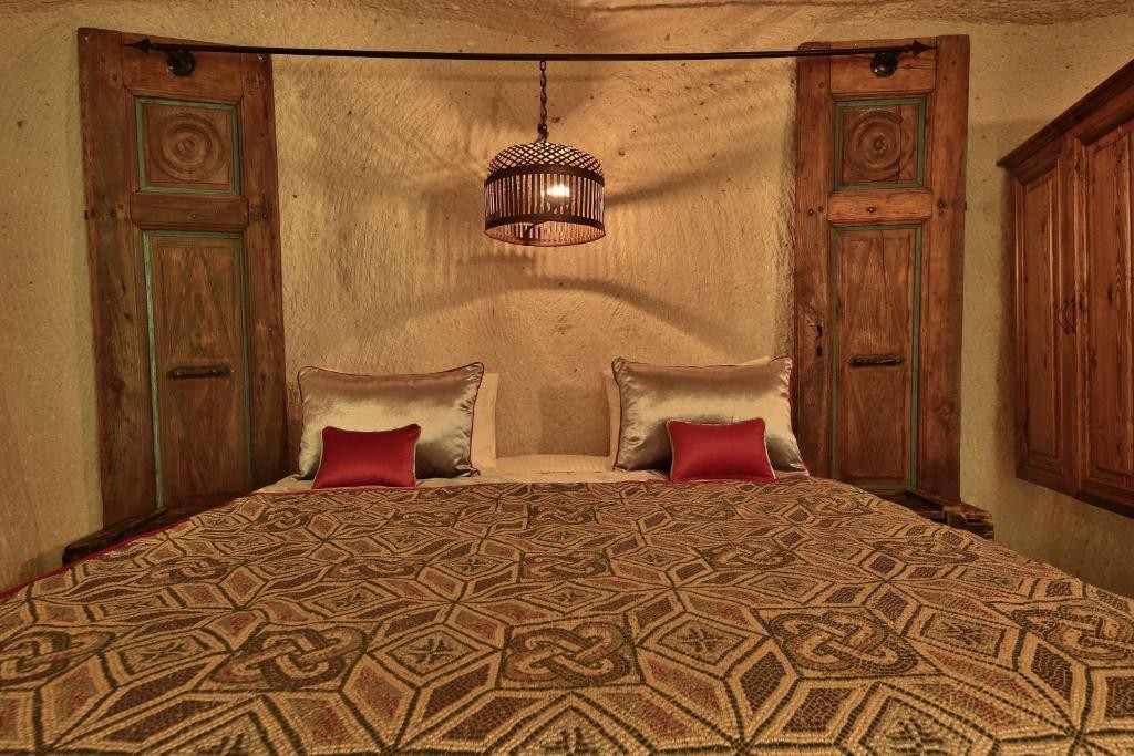 Deluxe King Suite king bed with carved wooden doors at The Owl Cave Hotel in Göreme, Cappadocia