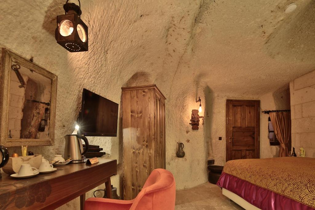Premier Cave Room cave interior with lantern lighting, desk, and king bed at The Owl Cave Hotel in Göreme