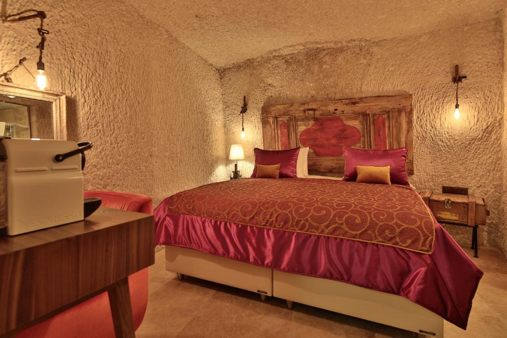 Superior Cave Room cave interior with coffee machine, seating, and king bed at The Owl Cave Hotel in Göreme